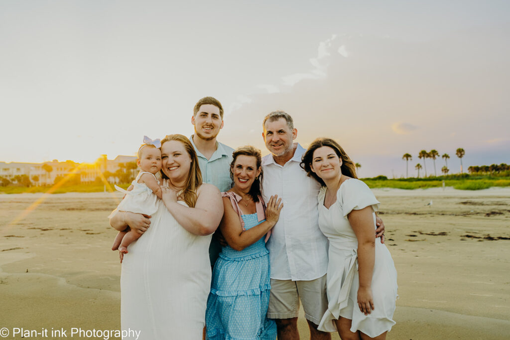 Meet Katie -Gentle Baby & Toddler Sleep Training Fort Worth A smiling family of six, including a baby held by her mother, stands together on the beach at sunset — a joyful reminder that understanding how to get a newborn to sleep at night helps parents feel connected, rested, and present for the moments that matter most.